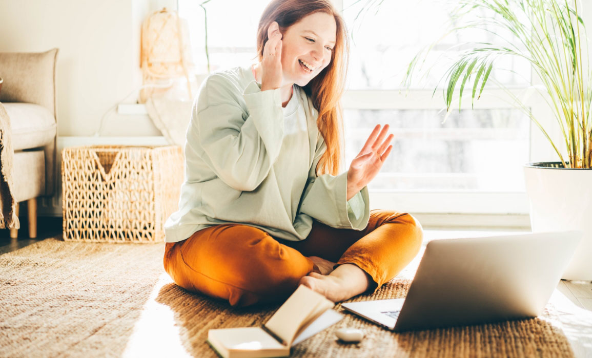 woman touching her ear and appears to be in harmony while looking at a laptop