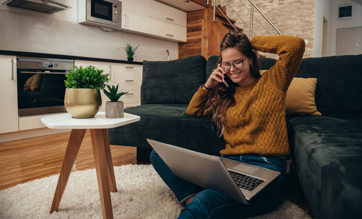 Woman listening happily on the phone while sitting inside a home