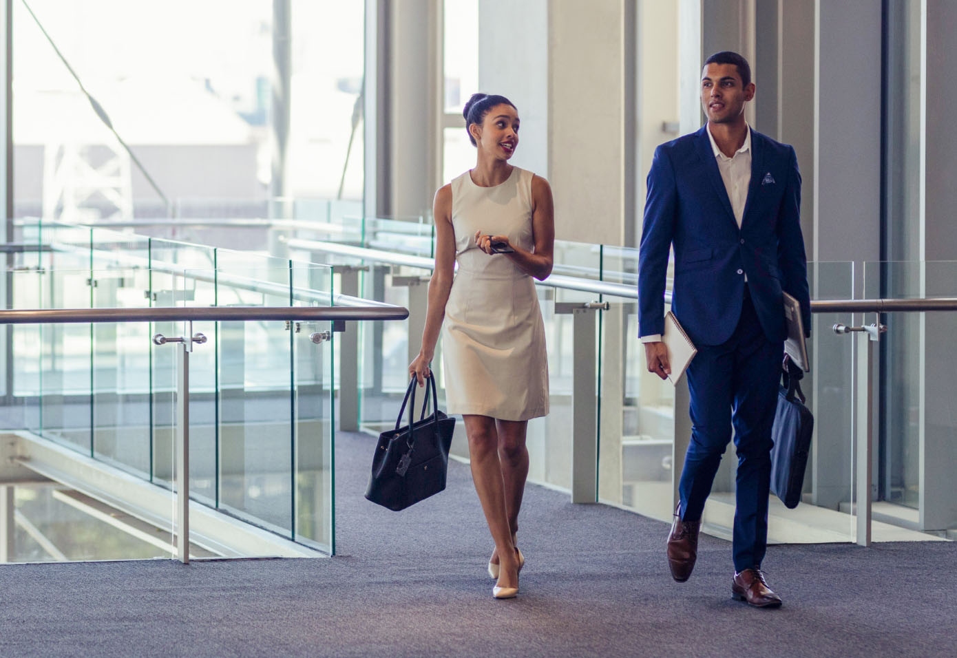 Two government employees walking outside in a public space, engaged in conversation