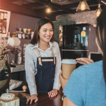 A barista smiling and conversing with a customer