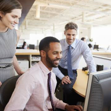 Professional looking people engaging with each other while looking at a computer screen