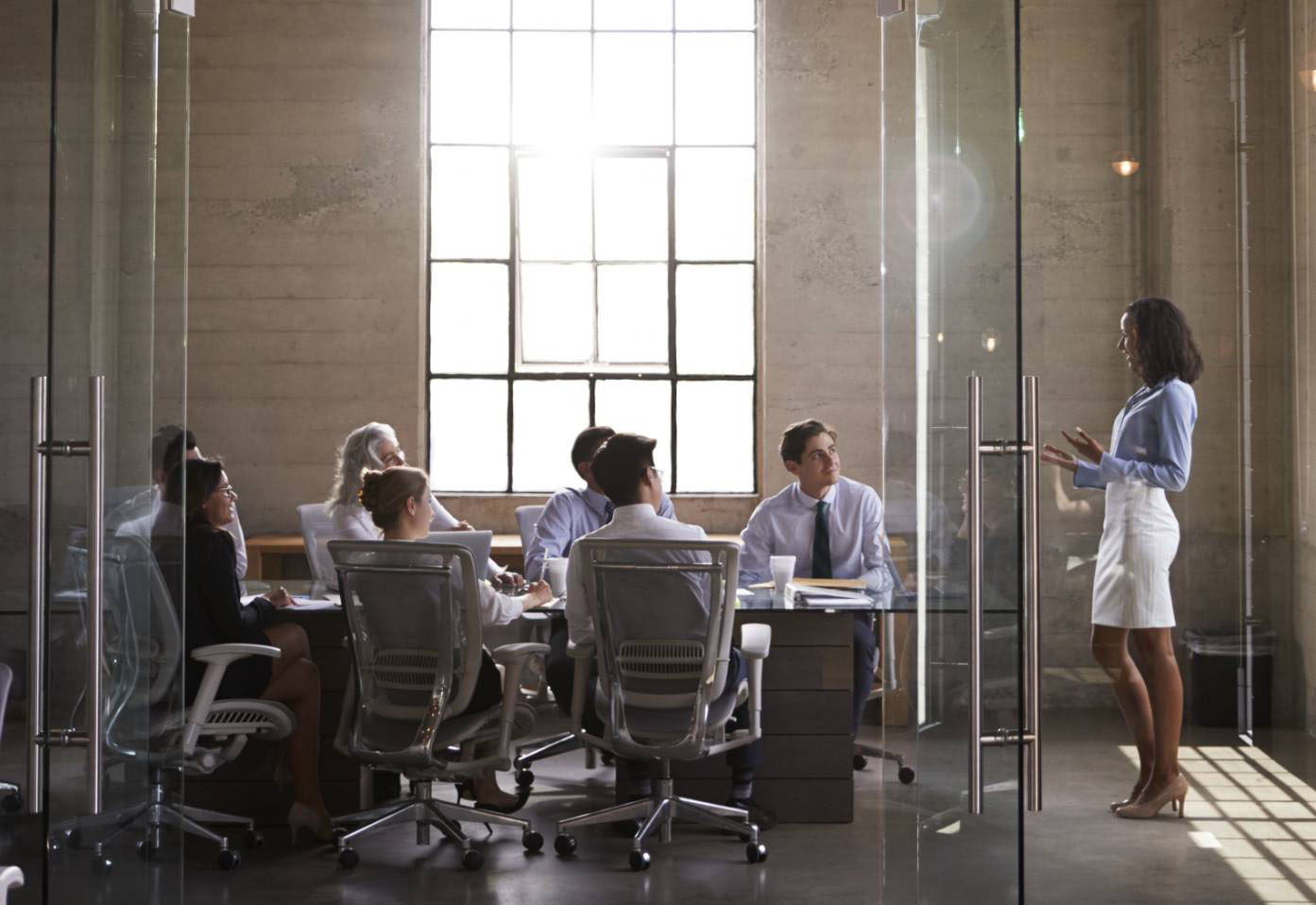 An image of a nice interior building, with a glass boardroom and people meeting in it