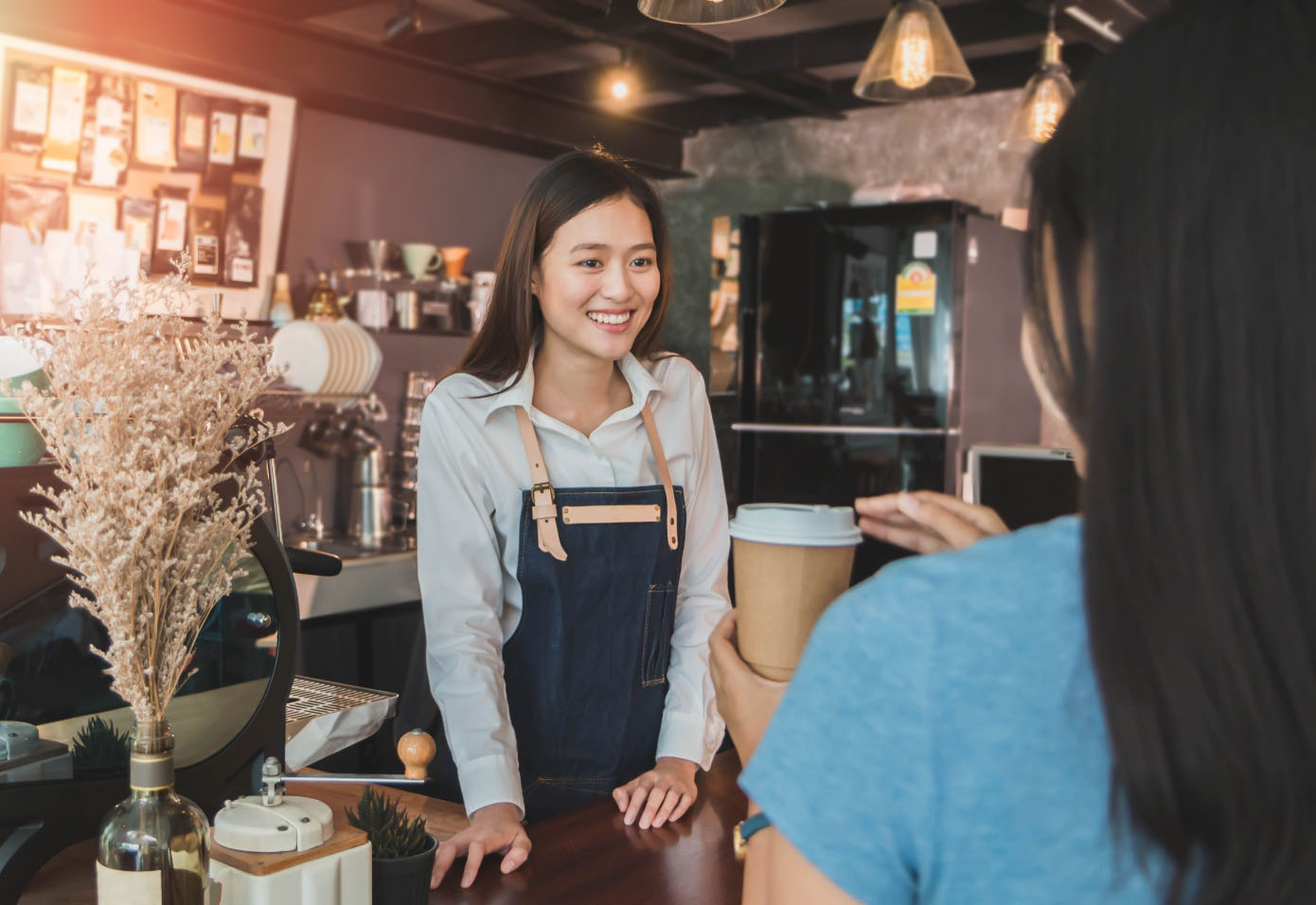 A barista smiling and conversing with a customer