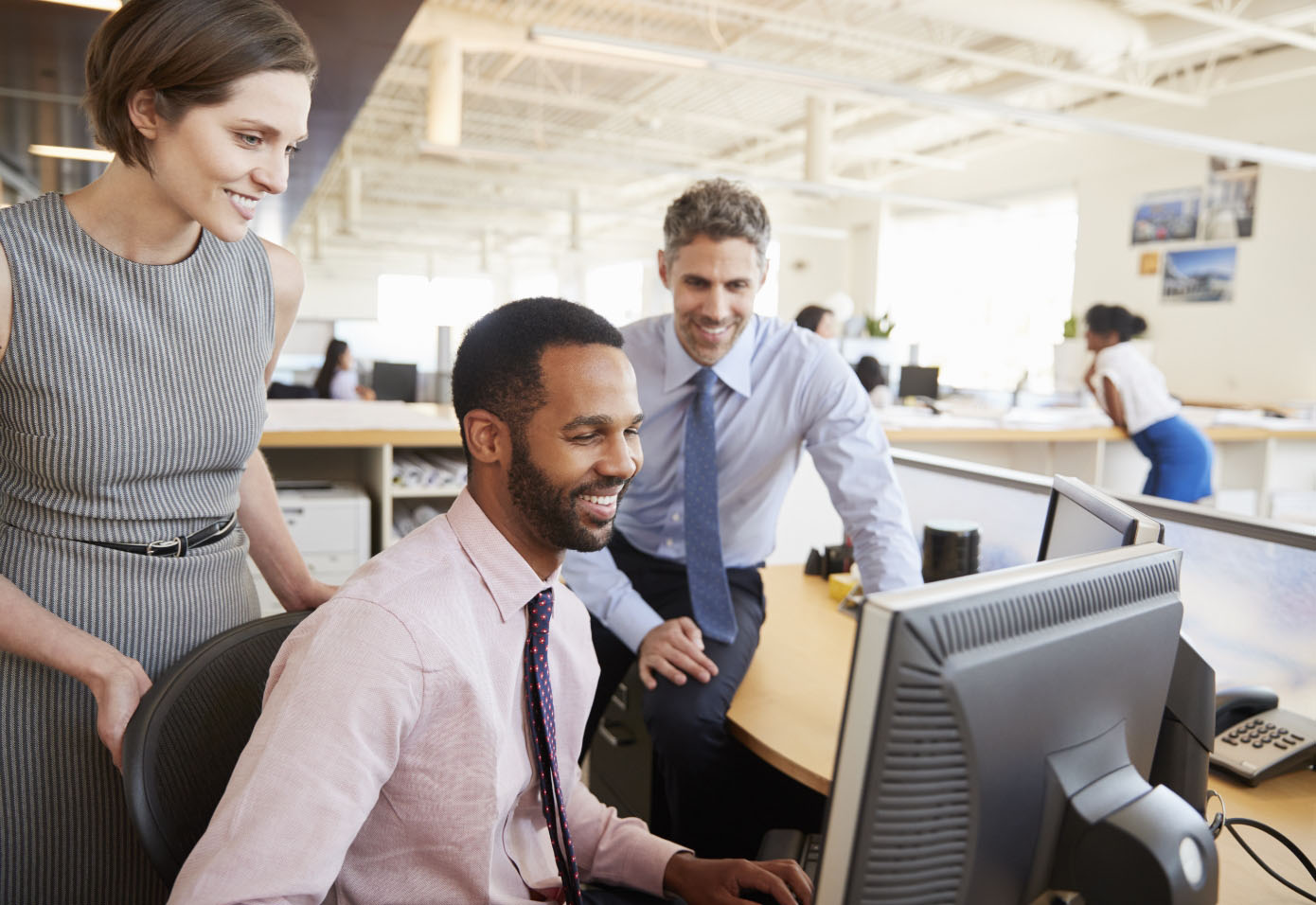 Professional looking people engaging with each other while looking at a computer screen