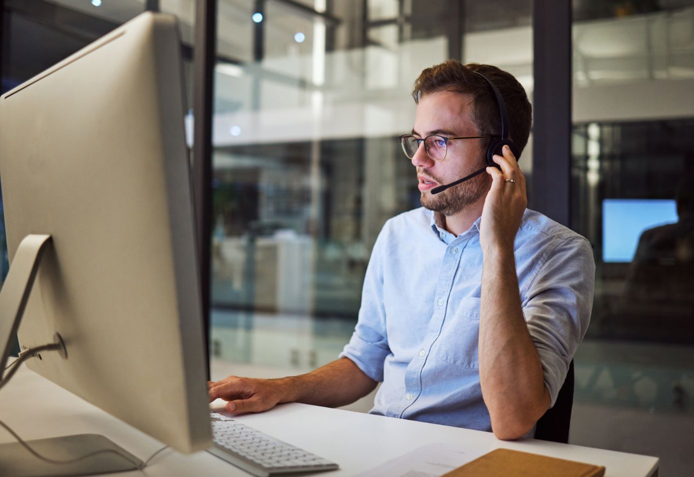 Professional on headphone with mic while looking at computer screen